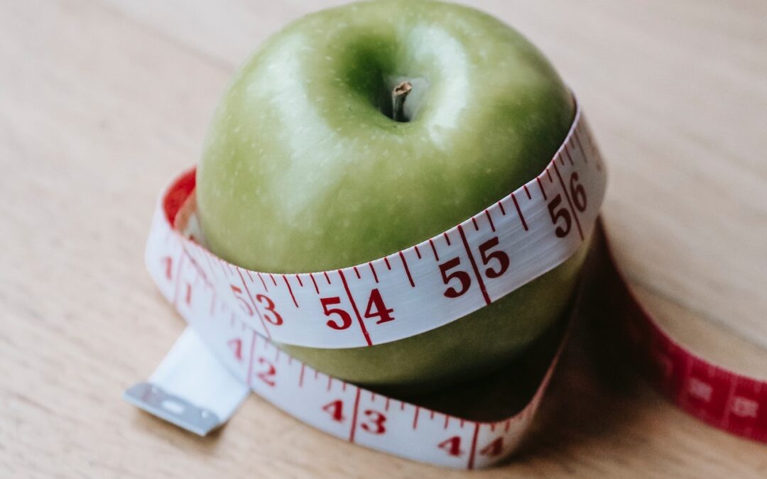 soczyste jabłko otoczone miarą krawiecką nawiązujące do funkcjonowania układu pokarmowego i przyspieszania metabolizmu