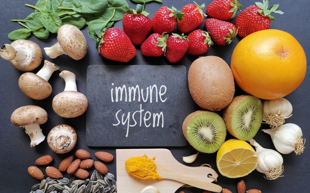 na tabliczce widnieje napis "układ odpornościowy", a wokół niej ułożone są zdrowe produkty wspomagające odporność: migdały, owoce, czosnek, kurkuma i szpinak